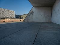 a skateboarder riding on a cement ramp next to a city street under a bridge