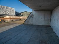 a skateboarder riding on a cement ramp next to a city street under a bridge