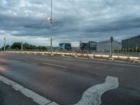 a road on an empty city street under a cloudy sky at dusk with traffic lights