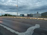 a road on an empty city street under a cloudy sky at dusk with traffic lights