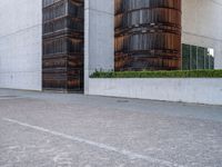 two wooden barrels are near some concrete buildings with bales on each side of them