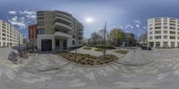 the view looking up at a building from inside of a 360 camera lens with some bicycles parked in front