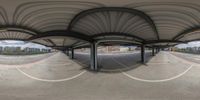 a panoramagraph image of an empty parking lot and street area as seen through the curved canopy