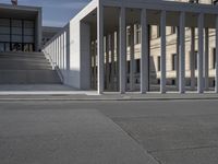 a person is standing outside on a skate board with an umbrella near the building that looks like it has columns and stairs