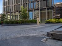 the side walk of a glass office building with concrete bricks and landscaping on each floor