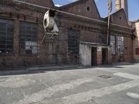 a cow hanging from the side of an old factory building by the doorways of the factory