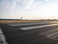 an empty runway with a cloudy sky above it and clouds in the background on the ground