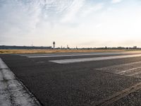 an empty runway with a cloudy sky above it and clouds in the background on the ground