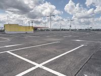 a parking lot with lots of empty parking spaces beneath cloudy skies and blue skies above