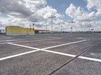 a parking lot with lots of empty parking spaces beneath cloudy skies and blue skies above