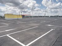 a parking lot with lots of empty parking spaces beneath cloudy skies and blue skies above