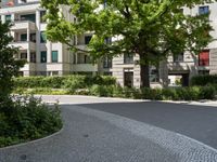 a parking space with a sign near a building in a park area that includes shrubs and trees and is a paved street