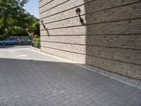 a row of four parking spots next to a brick wall that has a tree in the street