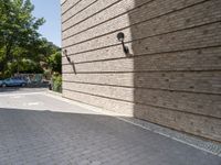 a row of four parking spots next to a brick wall that has a tree in the street