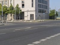 a view of an intersection in front of a building and street with cars driving on the road