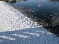 a snow covered canal with water and ice surrounding it, with buildings in the distance