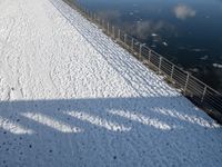 a snow covered canal with water and ice surrounding it, with buildings in the distance