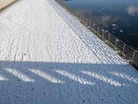 a snow covered canal with water and ice surrounding it, with buildings in the distance