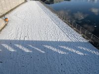 a snow covered canal with water and ice surrounding it, with buildings in the distance