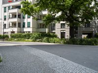 an apartment building with a parking area next to it and two tree in the center of the photo