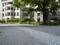 an apartment building with a parking area next to it and two tree in the center of the photo