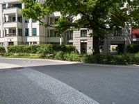 an apartment building with a parking area next to it and two tree in the center of the photo