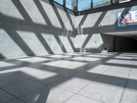 a large wall with an advertising sign on it next to windows in the building with the sunlight casting long shadows across the floor