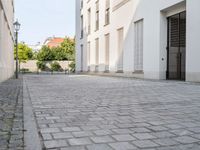 a small brick walkway in between two buildings with the door open and people walking on either side