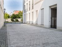 a small brick walkway in between two buildings with the door open and people walking on either side