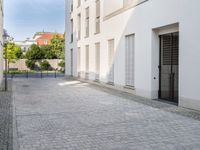 a small brick walkway in between two buildings with the door open and people walking on either side