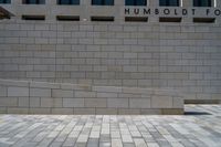 a person riding a skateboard near a stone wall and sign saying humboldt for science