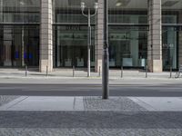 a woman on the street is standing by a pole that has been placed in front of a store