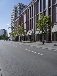 a deserted street with lots of windows and trees on the side of the road in front of it