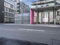 a large building is reflected in the side of the street that goes along this narrow road