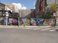 a wall with colorful graffiti near many tall buildings in a city area, including one building