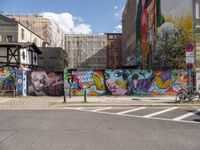 a wall with colorful graffiti near many tall buildings in a city area, including one building