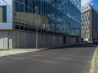 the street is quiet in front of a large glassy building with many windows and no one sitting on it