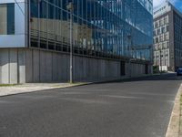 the street is quiet in front of a large glassy building with many windows and no one sitting on it