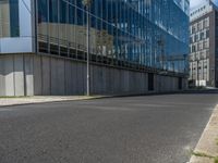 the street is quiet in front of a large glassy building with many windows and no one sitting on it