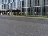 a man riding his skateboard down a empty city street in front of a glass office building