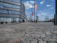 an image of a brick walkway on the side of the water near a tall building