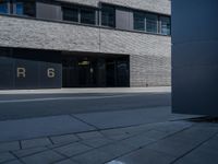 the exterior of a gray building with glass windows on the side walk with black and white logo in front