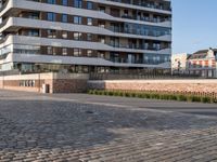 a man riding a skateboard down a cobblestone walkway next to tall buildings