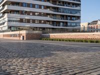 a man riding a skateboard down a cobblestone walkway next to tall buildings