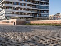 a man riding a skateboard down a cobblestone walkway next to tall buildings