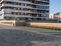 a man riding a skateboard down a cobblestone walkway next to tall buildings