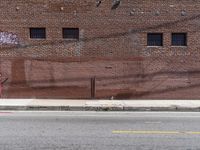 a red fire hydrant sits by the side of a road next to a brick building