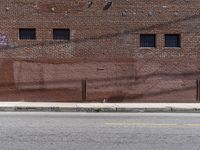 a red fire hydrant sits by the side of a road next to a brick building