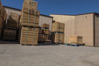 lots of wood are stacked in front of a building with a blue pallet full of wooden