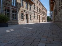 a view of a bricked side walk in an industrial building, with windows on two sides of the walkway